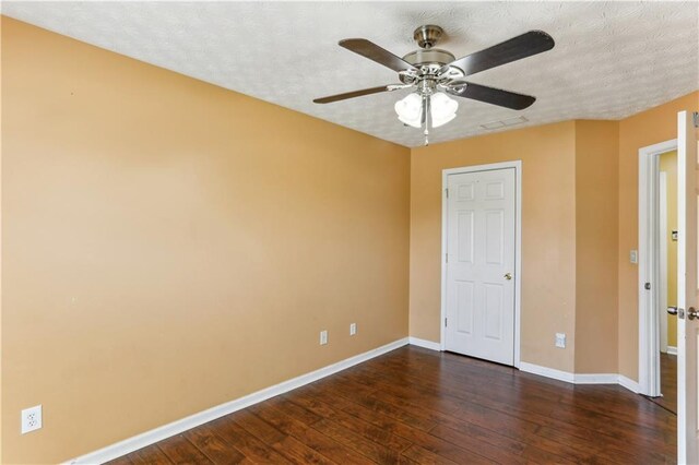 spare room with dark wood-type flooring, a textured ceiling, baseboards, and a ceiling fan