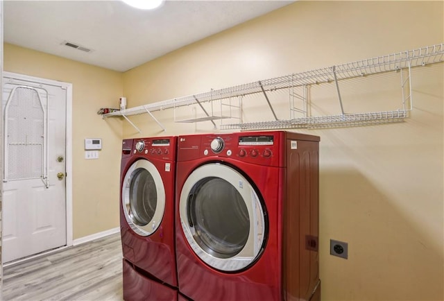 laundry room with baseboards, washing machine and clothes dryer, visible vents, laundry area, and wood finished floors
