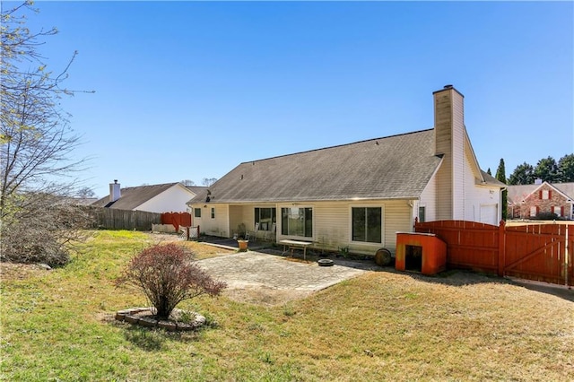 back of property featuring fence, a chimney, a patio, and a lawn