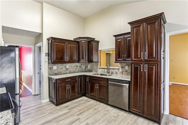 kitchen featuring light wood finished floors, tasteful backsplash, a sink, and stainless steel appliances