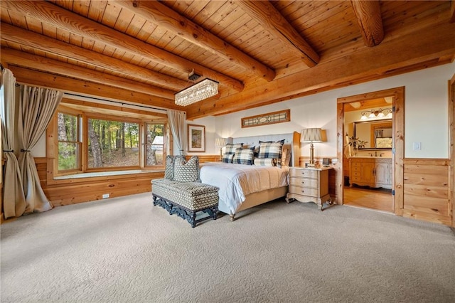 bedroom with beamed ceiling, ensuite bathroom, wooden ceiling, light colored carpet, and wooden walls