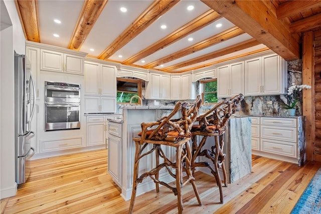 kitchen with white cabinets, appliances with stainless steel finishes, a center island, and a kitchen breakfast bar