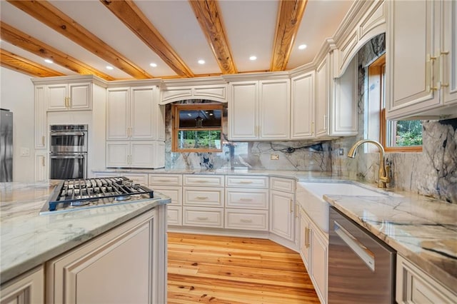 kitchen featuring light stone countertops, decorative backsplash, light hardwood / wood-style floors, appliances with stainless steel finishes, and beam ceiling