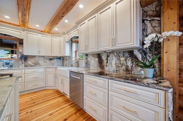 kitchen featuring beamed ceiling, light wood-type flooring, dark stone countertops, dishwasher, and backsplash