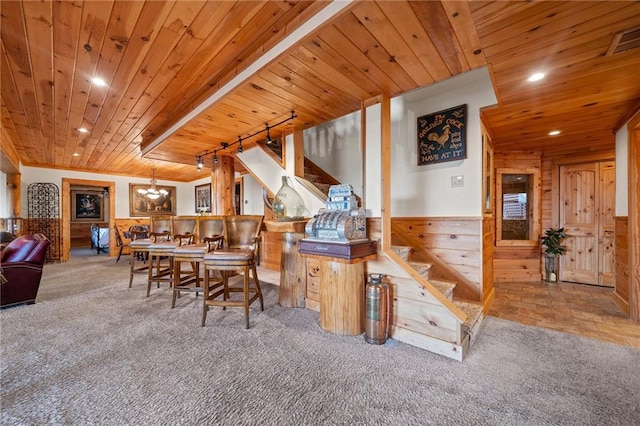 carpeted dining space featuring wood walls, wood ceiling, and a chandelier