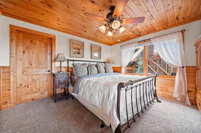 bedroom featuring ceiling fan, carpet floors, wooden walls, and wooden ceiling