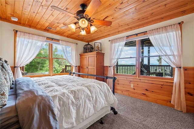 bedroom with wood walls, wooden ceiling, carpet flooring, and ceiling fan