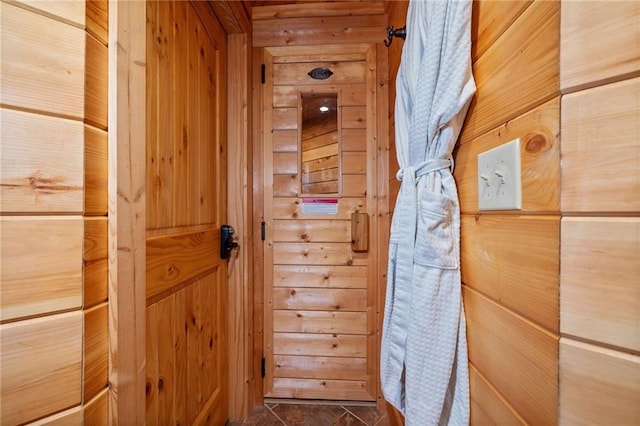 doorway to outside with wooden walls and dark tile patterned flooring