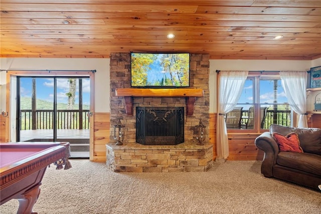 carpeted living room with pool table, wooden walls, a stone fireplace, and wood ceiling