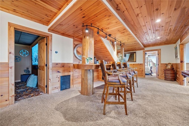 dining area featuring carpet floors, wooden ceiling, and wooden walls