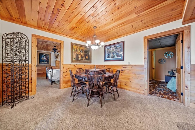 dining room with wood ceiling, wood walls, carpet floors, ceiling fan with notable chandelier, and crown molding