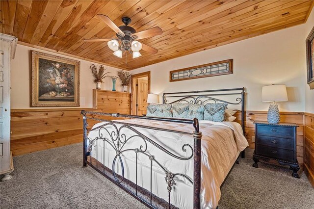 carpeted bedroom with ceiling fan, wood ceiling, and wood walls