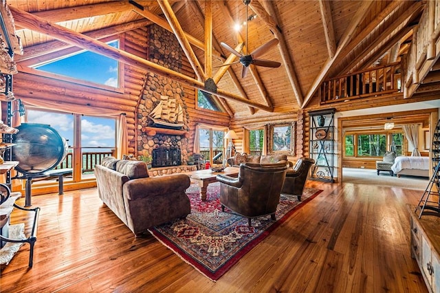 living room with a stone fireplace, light hardwood / wood-style floors, high vaulted ceiling, and a wealth of natural light