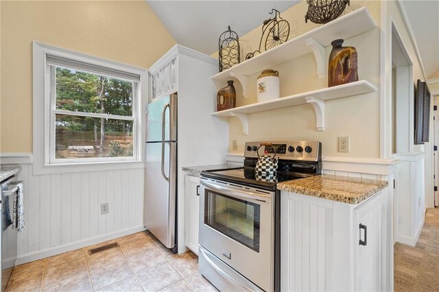 kitchen featuring white cabinets, appliances with stainless steel finishes, light tile patterned floors, and light stone countertops