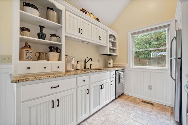 kitchen featuring light stone countertops, stainless steel appliances, sink, and white cabinetry