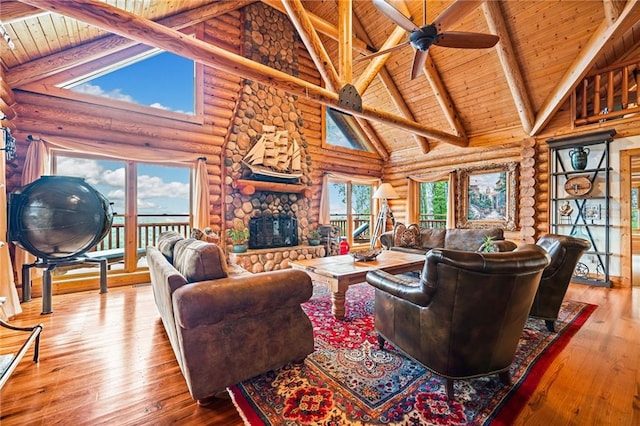 living room with high vaulted ceiling, hardwood / wood-style flooring, rustic walls, and a stone fireplace