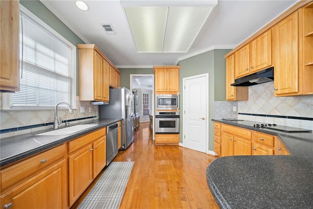 kitchen featuring visible vents, a sink, stainless steel appliances, under cabinet range hood, and crown molding