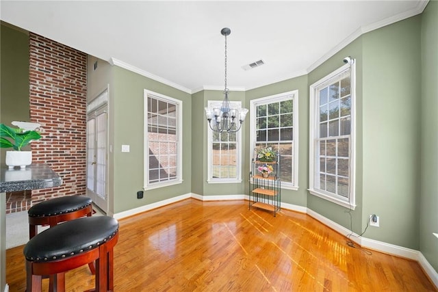 dining area with visible vents, baseboards, light wood-style flooring, crown molding, and a chandelier