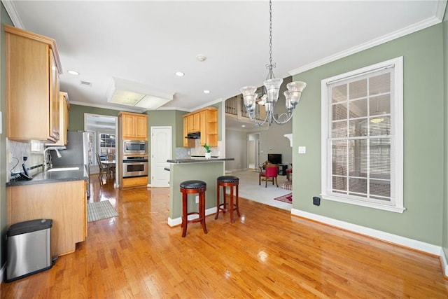 kitchen with crown molding, decorative backsplash, light wood-style flooring, appliances with stainless steel finishes, and a kitchen breakfast bar