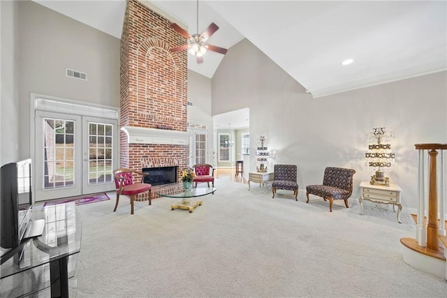 carpeted living room featuring visible vents, high vaulted ceiling, a fireplace, ceiling fan, and french doors