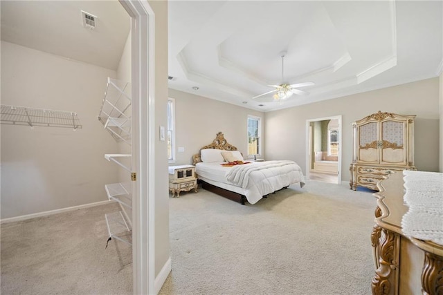 bedroom featuring visible vents, baseboards, light carpet, a raised ceiling, and a ceiling fan