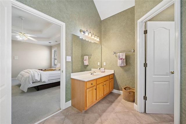 full bathroom with tile patterned flooring, connected bathroom, a tray ceiling, vanity, and a ceiling fan