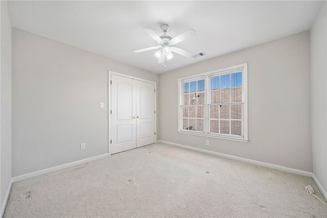 unfurnished bedroom with visible vents, ceiling fan, carpet, baseboards, and a closet