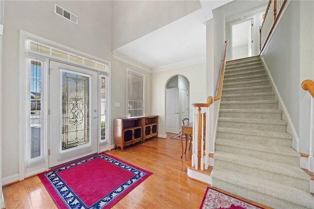 entrance foyer featuring stairway, wood finished floors, visible vents, baseboards, and arched walkways