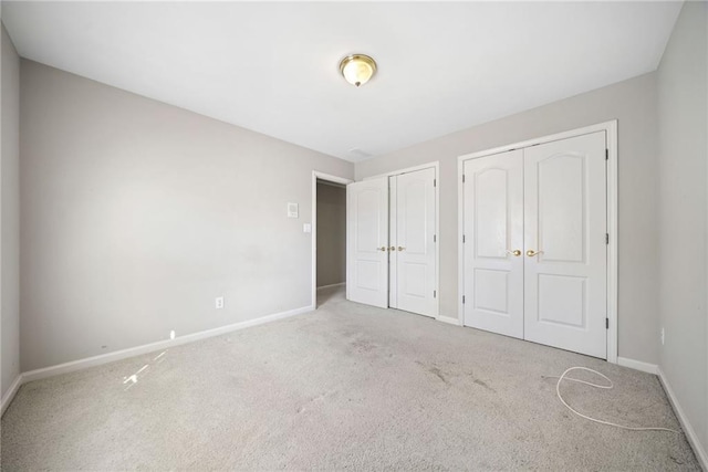 unfurnished bedroom with baseboards, two closets, and carpet floors