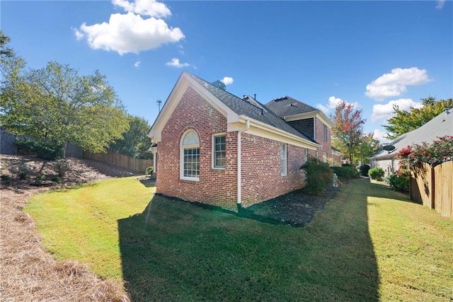 view of property exterior with brick siding, a fenced backyard, and a yard