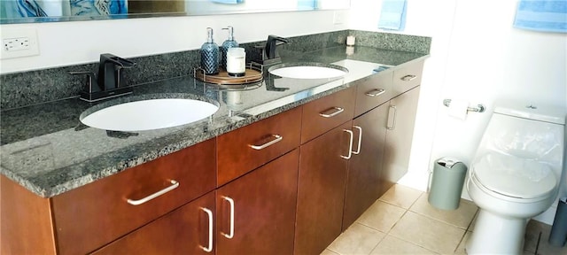 bathroom with toilet, tile patterned flooring, double vanity, and a sink