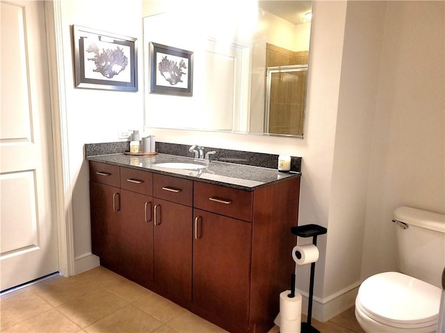 bathroom with toilet, a shower stall, vanity, baseboards, and tile patterned floors