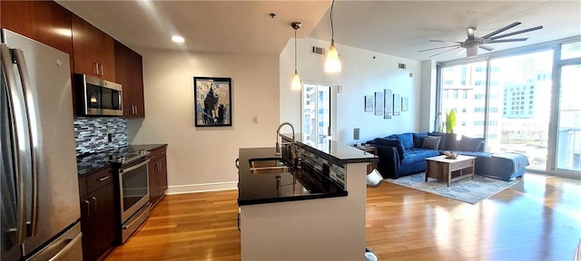 kitchen featuring appliances with stainless steel finishes, dark countertops, open floor plan, and pendant lighting