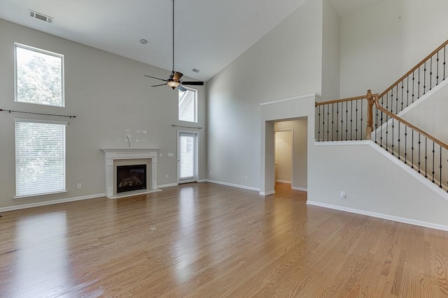 7719 Copper Kettle Way, Flowery Branch, GA 30542 - unfurnished living room with high vaulted ceiling, ceiling fan, light wood-type flooring, and a glass covered fireplace