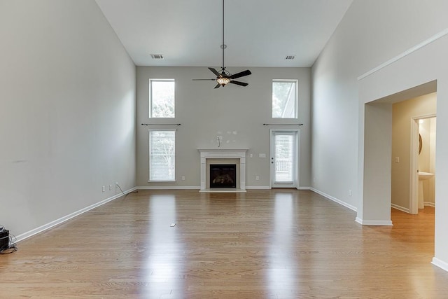 7719 Copper Kettle Way, Flowery Branch, GA 30542 - unfurnished living room featuring a towering ceiling, ceiling fan, plenty of natural light, and wood finished floors