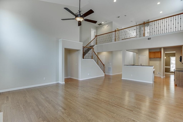 7719 Copper Kettle Way, Flowery Branch, GA 30542 - unfurnished living room with a high ceiling, a ceiling fan, light wood-type flooring, stairway, and recessed lighting