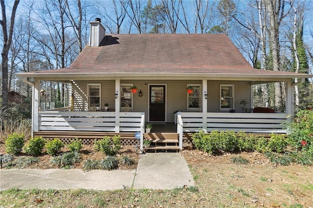 farmhouse featuring covered porch and a chimney