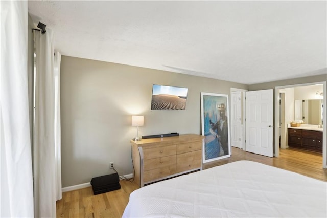 bedroom featuring connected bathroom, baseboards, and wood finished floors