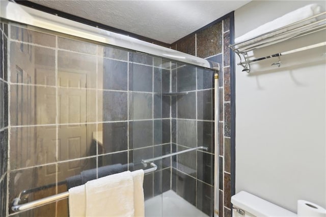 bathroom with a shower stall, a textured ceiling, and toilet