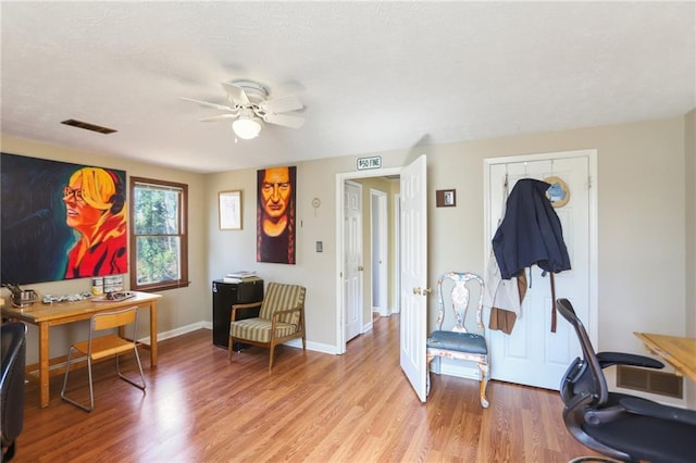 home office featuring light wood-type flooring, visible vents, baseboards, and a ceiling fan