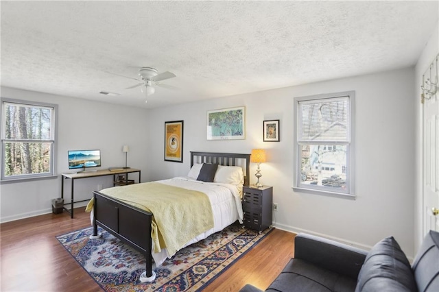 bedroom with baseboards, a textured ceiling, and wood finished floors