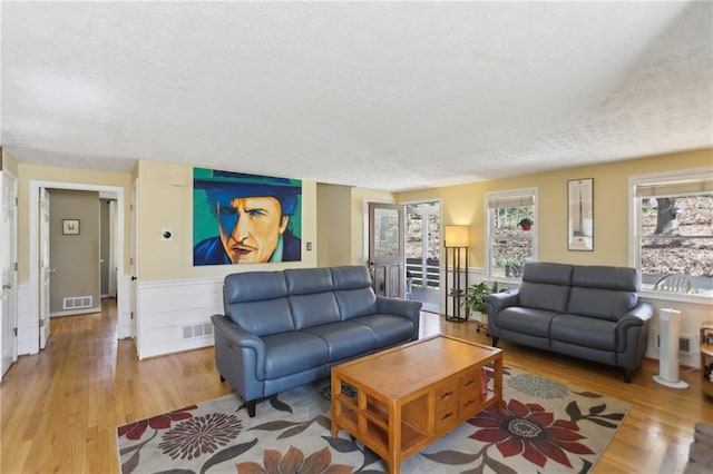 living area with visible vents, plenty of natural light, and wood finished floors