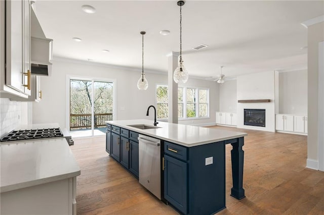 kitchen featuring dishwasher, decorative light fixtures, blue cabinets, sink, and a kitchen island with sink