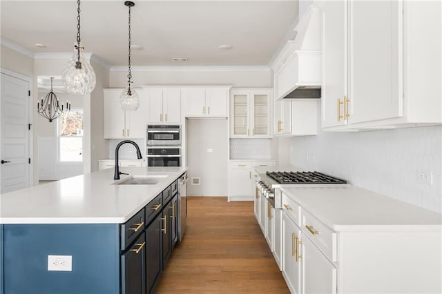 kitchen featuring appliances with stainless steel finishes, an island with sink, white cabinets, pendant lighting, and sink