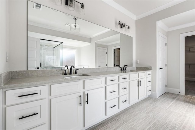 bathroom with vanity, crown molding, and a shower with door