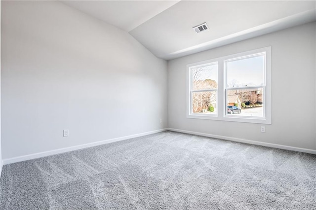 carpeted spare room featuring vaulted ceiling