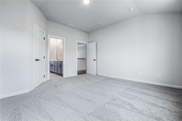 unfurnished bedroom featuring vaulted ceiling, ensuite bathroom, and light colored carpet