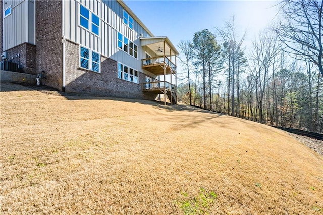 view of yard with central AC unit, ceiling fan, and a balcony