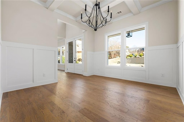 unfurnished dining area with coffered ceiling, beamed ceiling, dark hardwood / wood-style floors, and a notable chandelier