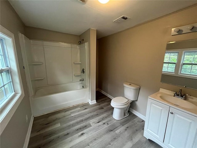 full bathroom with toilet, vanity, hardwood / wood-style floors, and washtub / shower combination